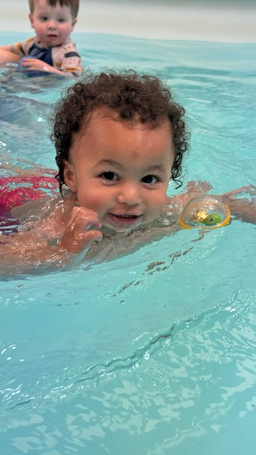 A happy child swimming towards the camera during a lesson